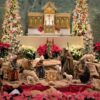 Photo of the sanctuary, with the Nativity scene surrounded by poinsettias and Christmas trees.