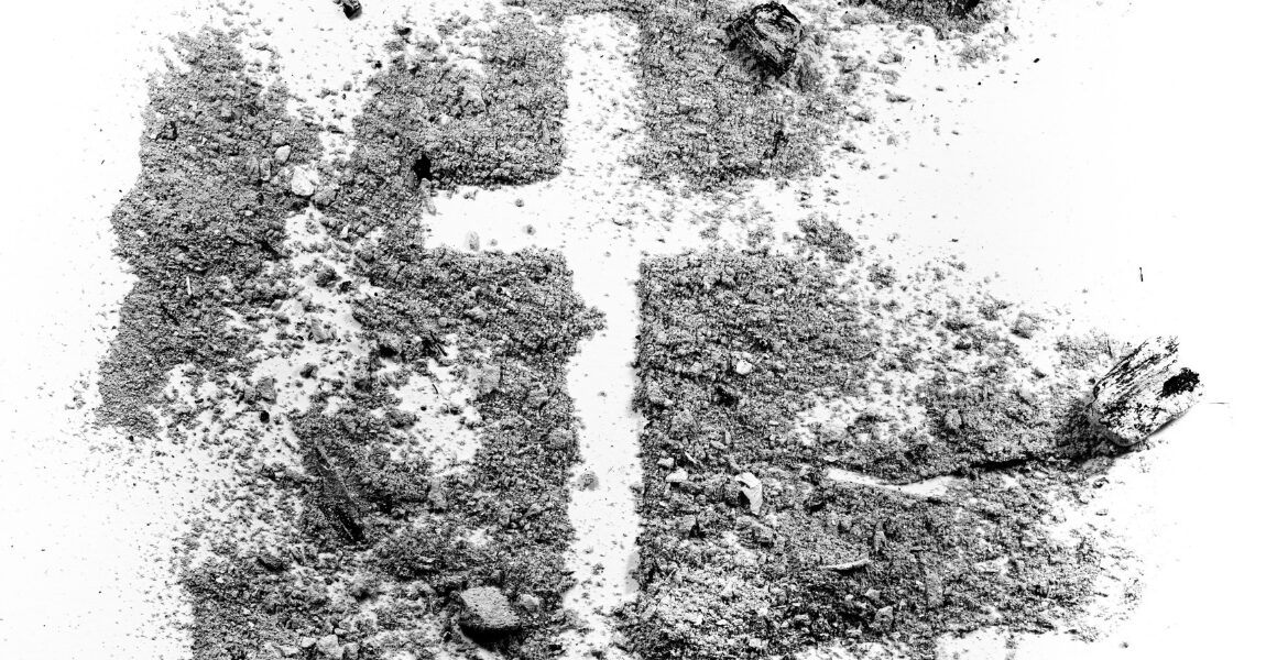 A cross outlined in dirt on the ground.